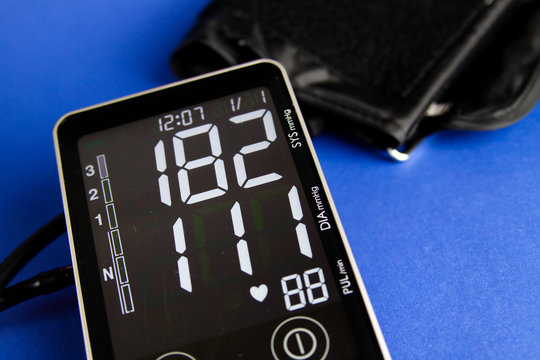 Close up of digital monitor device with cuff showing high diastolic and systolic blood pressure