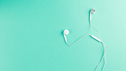 Flat lay concept: headphone on Mint backgrounds. White headphones on a Mint background, top view, copy space. Minimal style with colorful paper backdrop. Neo Mint color of the year 2020