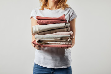 Cropped view of woman holding folded ironed clothes isolated on grey