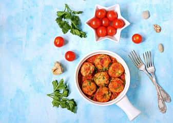 Fish meatballs in tomato sauce in a white ceramic pan on a light blue concrete background. Top view, copy space.
