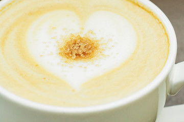 close up of big cup of freshly brewed cappuccino with soft foam and brown sugar and drawing heart by barista
