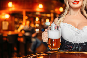 Large breasted waitress  holds mug of fresh beer