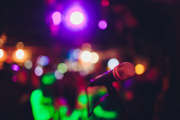 Microphone on a stand ready for live music performance or karaoke night with soft bokeh lights and...