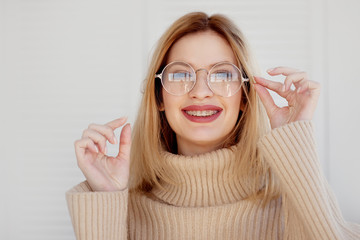 Stylish and beautiful young blonde with glasses and beige oversize sweater.