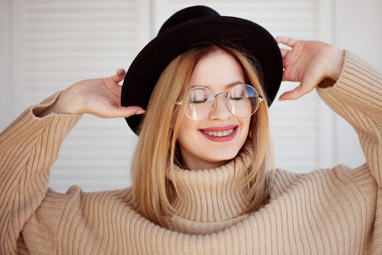 Charming young girl in a stylish hat and glasses. Young woman wearing braces and smiling