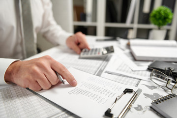 Fototapeta premium Businessman working at office and calculating finance, reads and writes reports. Business financial accounting concept.