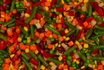 Sliced vegetables, corn, beans, peas, carrots, sweet peppers background.