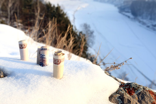 Paper Money Stuck In The Snow In The Background Of Snowy Forests And Rivers Under The Ice