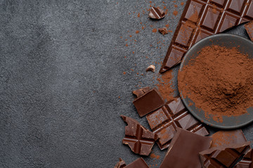 Frame or border made of Dark or milk organic chocolate pieces and cocoa powder on dark concrete...