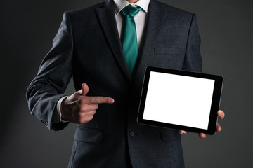 Digital tablet computer with a blank screen in a business man hands on gray background. Special offer mock up. Business proposal template. Contact us phone number background with copy space.