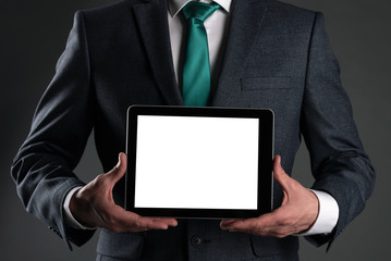 Digital tablet computer with a blank screen in a business man hands on gray background. Special offer mock up. Business proposal template. Contact us phone number background with copy space.