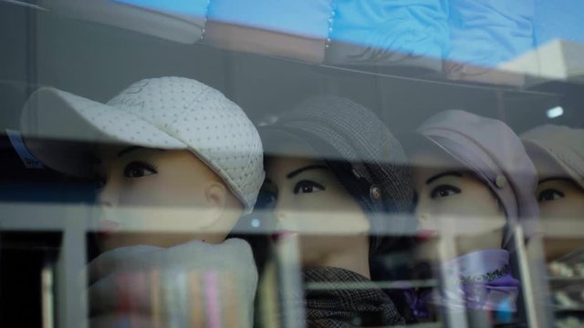 Shop window. Caps and scarves on mannequins. Female plastic heads. Shopping women's clothing. Problem of choice of clothes. Shopping street. Boutique shopping center