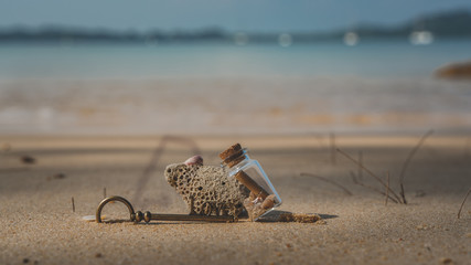 Key And Message In Bottle On Beach