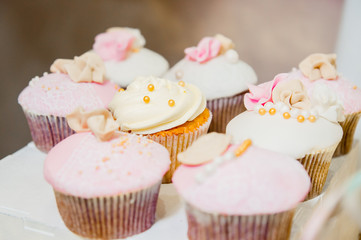 some cupcakes with white and pink cream and golden sparkles