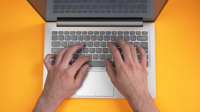 Using a laptop computer top view on a orange desk