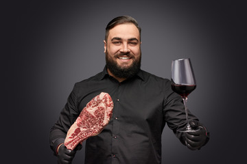 Smiling overweight man with meat and wine