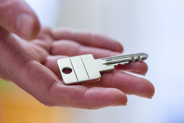 Moving into a new home: Close up of a hand holding a key. Property and real estate.