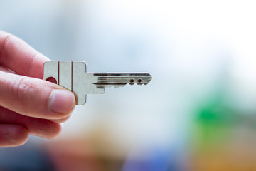 Moving into a new home: Close up of a hand holding a key. Property and real estate.