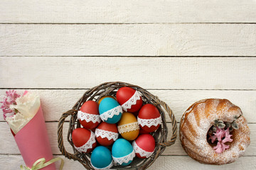 Wielkanocne tło - kolorowe pisanki w koszyku, babka wiekanocna i wiosenne kwiaty