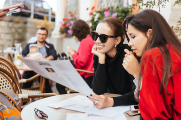 Two beautiful stylish women sitting at the table in street cafe