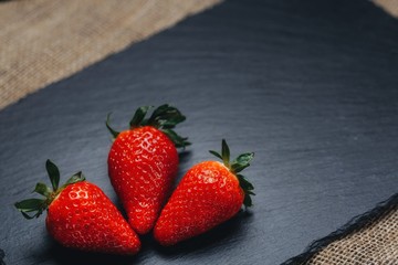 Three strawberries on gray stone. Three strawberries on a gray stone background