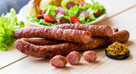 Smoked sausage with vegetables salad and mustard on a wooden board
