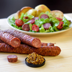 Smoked sausage with vegetables salad and mustard on a wooden board