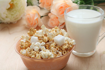 Cup of popcorn and a mug of milk on a wooden table close-up, tasty breakfast and a good start to the day