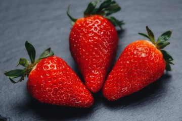 Three strawberries on gray stone. Three strawberries on a gray stone background