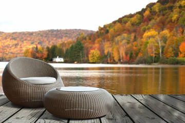 A set of round wicker chair on old wooden deck with view of  lake and colorful forest in Autumn .