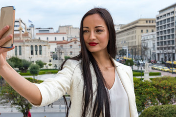 Elegant woman is taking a selfie photo with her smart phone