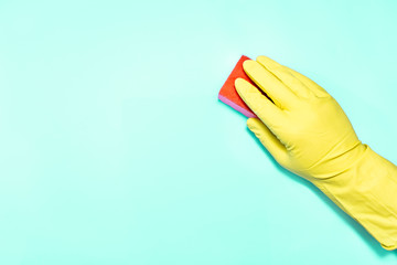 Man hand in glove with sponge on turquoise background.