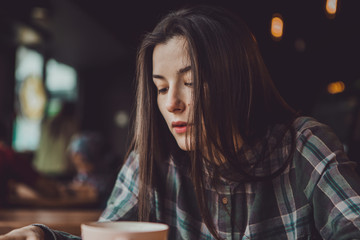 Portrait of a happy smiling brunette girl who holds in the hand of a mobile phone rewriting in social networks with friends or reading news