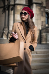 Young beautiful woman with long brown hair in sunglasses on a walk on a cloudy day. Fashionable sexy girl. Street fashion look. Cute student. Shopping.