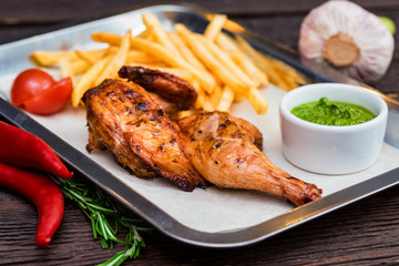 Close up meal with chicken thigh, french fries, chili pepper and garlic
