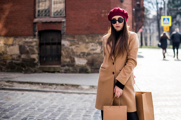 Young beautiful woman with long brown hair in sunglasses on a walk on a cloudy day. Fashionable sexy girl. Street fashion look. Cute student. Shopping.