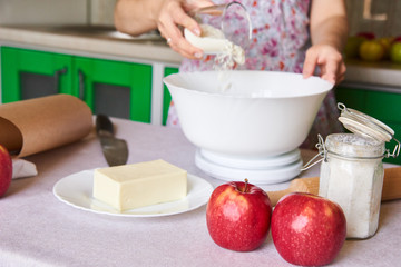 woman in rustic dress weighing the flour on the table with ingredients for american apple pie