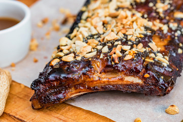 Close up board with pork ribs grilled with BBQ sauce and peanuts
