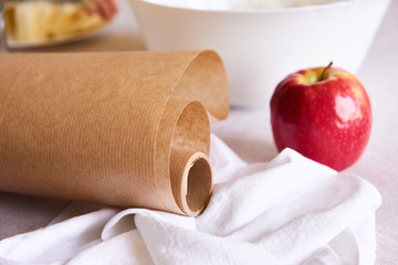 bowl of flour towel, parchment paper and ripe apple on the white table - kitchen concept