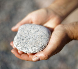 Closeup of female hands holding a stone in warm evening light