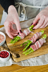 The chef prepares mini asparagus in bacon. Side view, the background of the kitchen, concept of cooking food balanced diet.