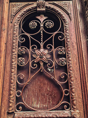 Detail of wooden door of a building on the street with an iron decorative ornament. Old Tbilisi architecture