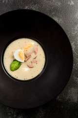Homemade sour soup served with egg on dark plate