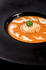 Homemade tomato soup served on dark plate