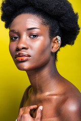 Pensive attractive african american woman with ear cuff on yellow