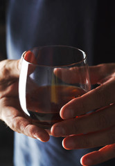 A glass of cognac in male hands.
