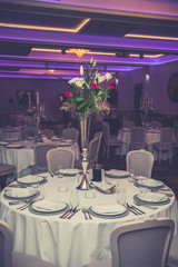 Restaurant table decoration or setting for wedding party. Glass vase with red and white roses in middle of table.