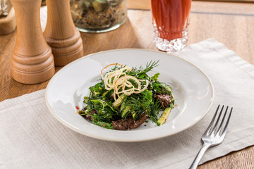 Spicy Beef Salad with green mix and tomato juice on wooden table