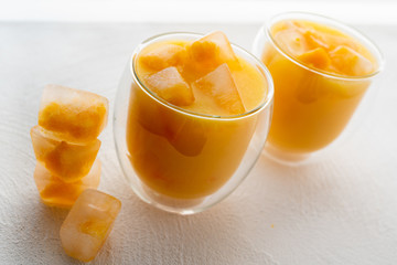  Orange Juice With Ice Cubes in Glasses Close Up. Ice Cubes With Small Pieces of Frozen Oranges