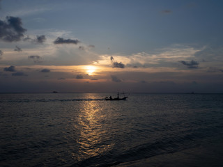 Fototapeta na wymiar Silhouettes of people in a kayak in the rays of the setting sun against the background of clouds. Ko Phangan.Thailand.